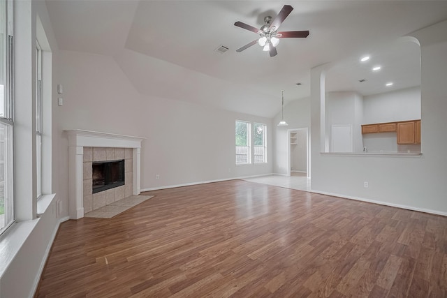 7407 Breda Dr, Baytown, TX 77521 - unfurnished living room with lofted ceiling, a ceiling fan, a tiled fireplace, wood finished floors, and baseboards