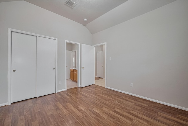 7407 Breda Dr, Baytown, TX 77521 - unfurnished bedroom featuring lofted ceiling, light wood-type flooring, baseboards, a closet, and ensuite bathroom
