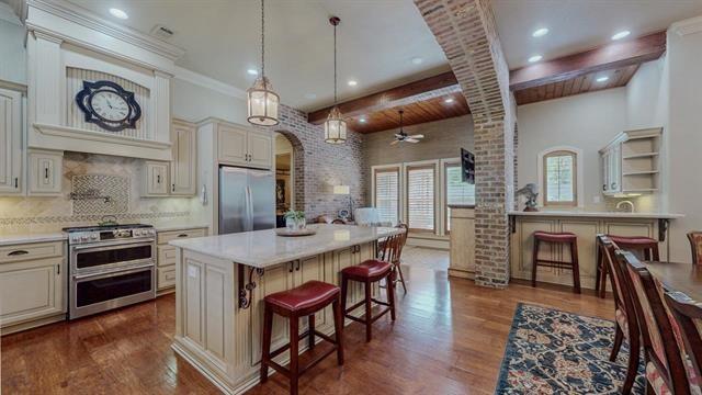 7705 Savannah, Beaumont, TX 77707 - kitchen featuring stainless steel appliances, arched walkways, a kitchen breakfast bar, dark wood-style floors, and beamed ceiling