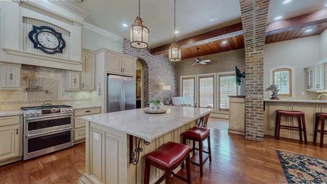 7705 Savannah, Beaumont, TX 77707 - kitchen featuring appliances with stainless steel finishes, cream cabinetry, arched walkways, backsplash, and a kitchen breakfast bar