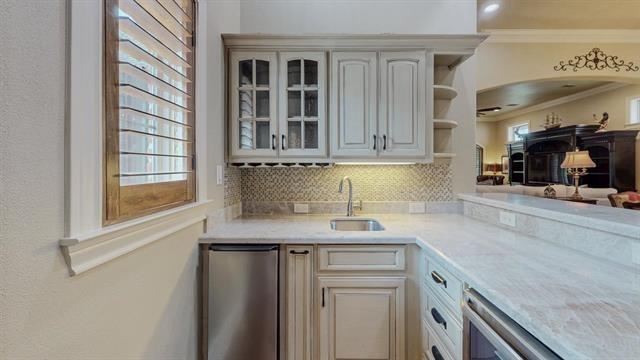 7705 Savannah, Beaumont, TX 77707 - kitchen featuring a sink, ornamental molding, refrigerator, glass insert cabinets, and open shelves