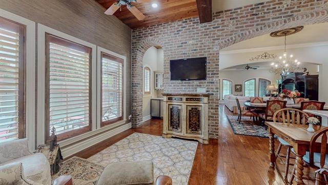 7705 Savannah, Beaumont, TX 77707 - living area with a ceiling fan, a fireplace, wood finished floors, a chandelier, and brick wall