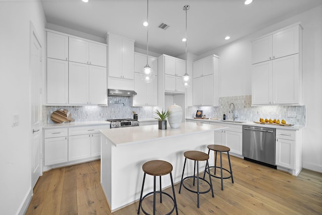 1705 Bologna Ln, Houston, TX 77055 - kitchen with appliances with stainless steel finishes, under cabinet range hood, a sink, white cabinetry, and light countertops