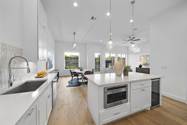 1705 Bologna Ln, Houston, TX 77055 - kitchen featuring a sink, stainless steel appliances, beverage cooler, recessed lighting, and light wood finished floors