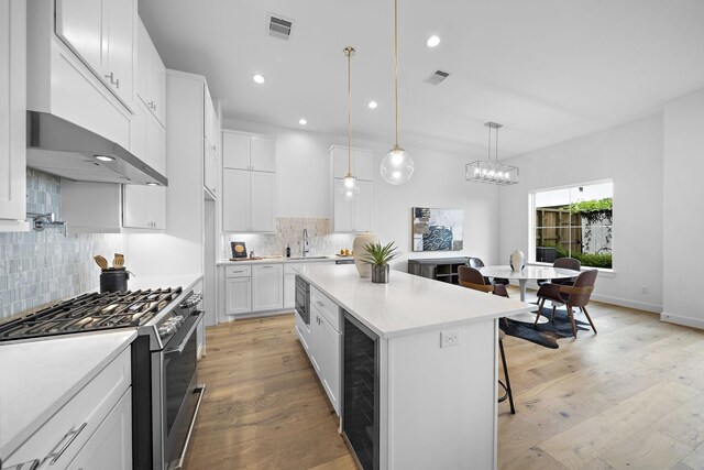 1705 Bologna Ln, Houston, TX 77055 - kitchen with appliances with stainless steel finishes, wine cooler, a sink, light countertops, and tasteful backsplash
