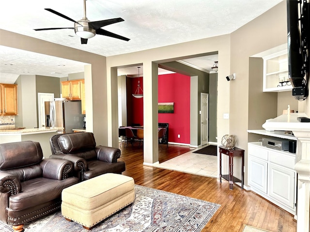 8910 Everhart Ln, Houston, TX 77040 - living room with light wood-type flooring, a ceiling fan, a textured ceiling, and baseboards