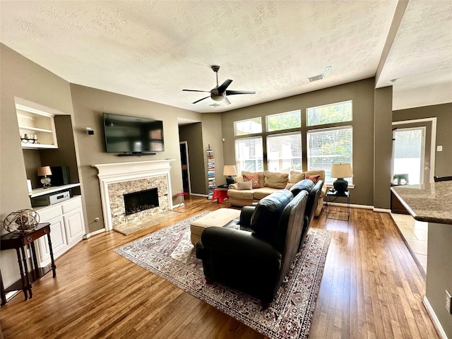 8910 Everhart Ln, Houston, TX 77040 - living room with a textured ceiling, hardwood / wood-style floors, a ceiling fan, a tiled fireplace, and built in shelves