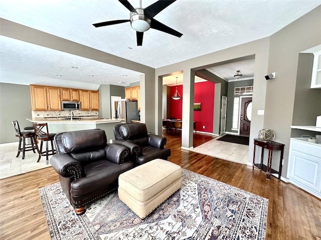 8910 Everhart Ln, Houston, TX 77040 - living room featuring ceiling fan, light wood-style floors, baseboards, and a textured ceiling
