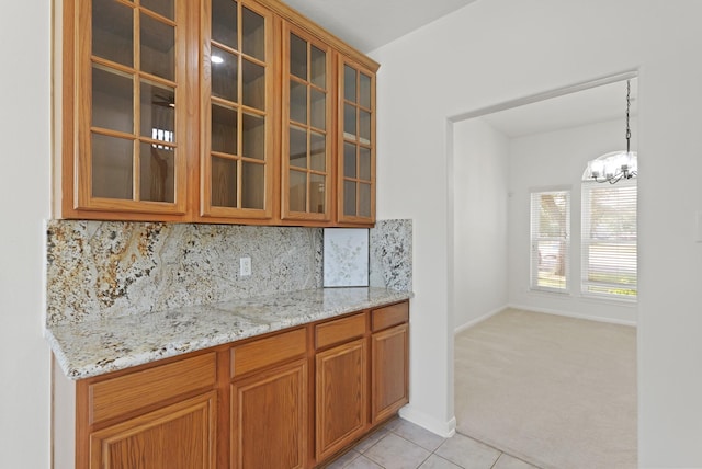 6426 Savannah Pines Dr, Katy, TX 77449 - kitchen with glass insert cabinets, light stone counters, backsplash, and light tile patterned floors