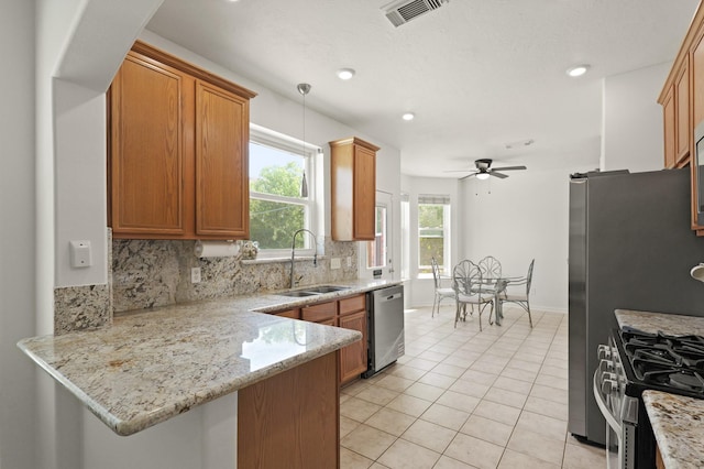6426 Savannah Pines Dr, Katy, TX 77449 - kitchen featuring a sink, appliances with stainless steel finishes, tasteful backsplash, a peninsula, and brown cabinetry