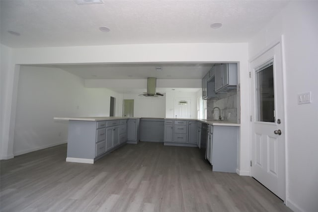 345 Byrd St, Vidor, TX 77662 - kitchen with gray cabinets, wall chimney exhaust hood, a peninsula, a sink, and light wood finished floors