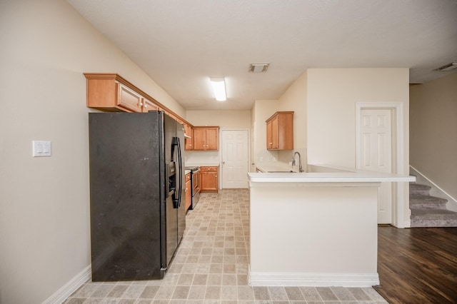 12510 Panther Place Dr, Houston, TX 77099 - kitchen with black fridge with ice dispenser, a peninsula, light countertops, electric range, and brown cabinetry