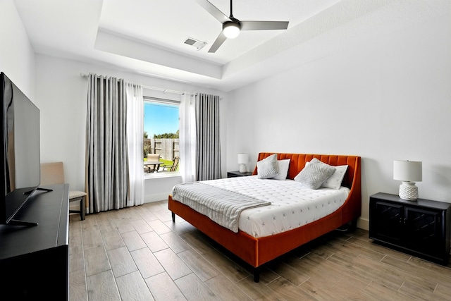 16522 N Canyon Trace Dr, Houston, TX 77095 - bedroom with a tray ceiling, light wood-style flooring, a ceiling fan, and baseboards