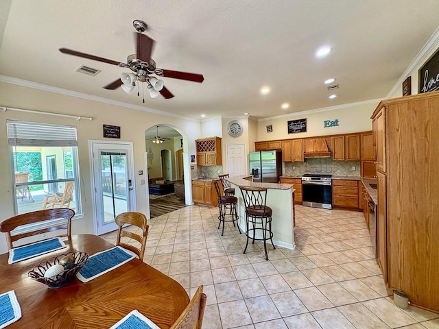 18 Joe Werner Ln, Huntsville, TX 77320 - kitchen featuring stainless steel appliances, arched walkways, a ceiling fan, backsplash, and brown cabinets