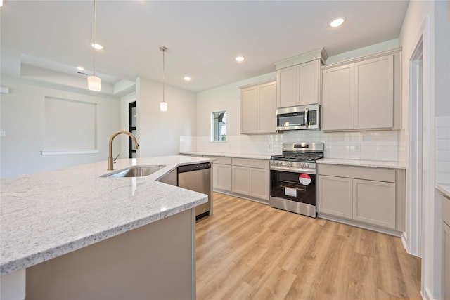 540 Barton Place Dr, Cleveland, TX 77327 - kitchen with stainless steel appliances, a sink, light wood-style floors, decorative backsplash, and pendant lighting