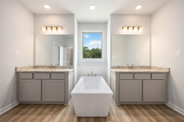 540 Barton Place Dr, Cleveland, TX 77327 - bathroom featuring wood finished floors, a soaking tub, and two vanities