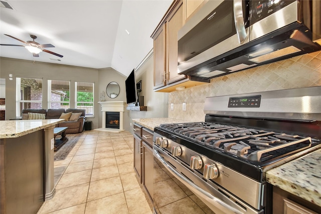 1586 Ancient Oak Ln, Conroe, TX 77301 - kitchen with appliances with stainless steel finishes, a ceiling fan, decorative backsplash, light tile patterned floors, and a lit fireplace