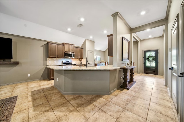 1586 Ancient Oak Ln, Conroe, TX 77301 - kitchen with appliances with stainless steel finishes, light tile patterned flooring, light stone countertops, tasteful backsplash, and crown molding