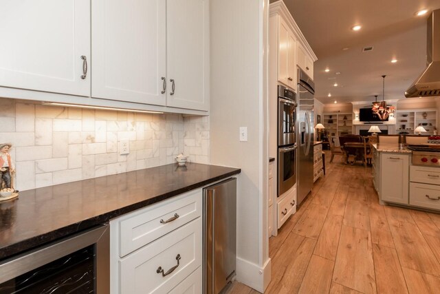5950 Keith Rd, Lumberton, TX 77657 - kitchen with wine cooler, open floor plan, tasteful backsplash, white cabinetry, and wall chimney exhaust hood