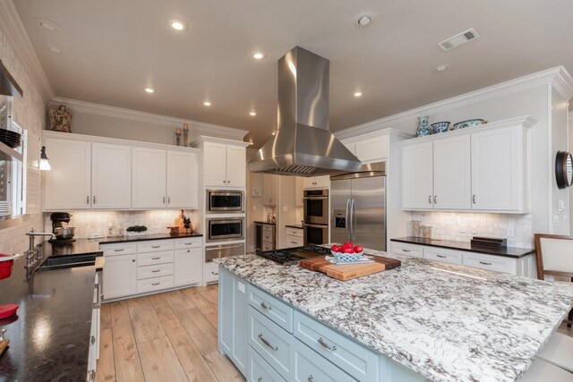 5950 Keith Rd, Lumberton, TX 77657 - kitchen with island exhaust hood, built in appliances, white cabinetry, backsplash, and ornamental molding