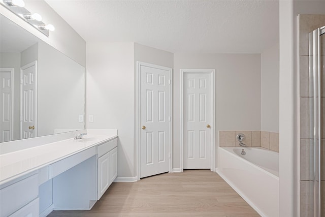 1219 Newsome Glenn Dr, Houston, TX 77090 - bathroom with vanity, wood finished floors, a bath, a textured ceiling, and a shower with door