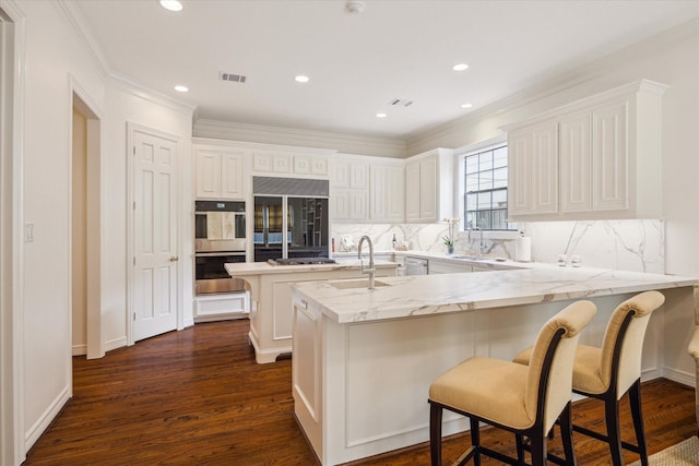 2214 Potomac Dr Unit 2, Houston, TX 77057 - kitchen featuring backsplash, a peninsula, appliances with stainless steel finishes, a center island with sink, and a kitchen bar