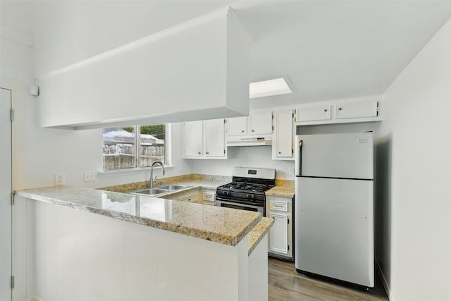2079 Country Village Blvd Unit C, Humble, TX 77338 - kitchen featuring freestanding refrigerator, a sink, gas stove, under cabinet range hood, and a peninsula