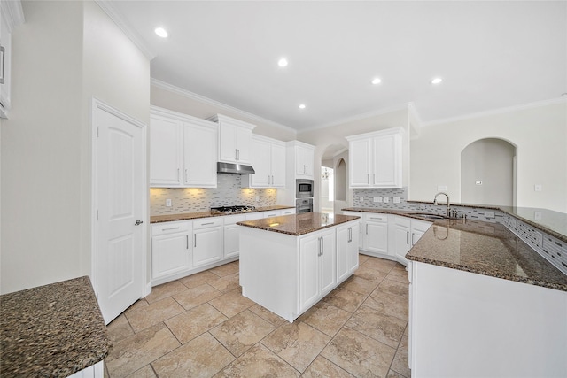 27910 Wedgeoak Ct, Katy, TX 77494 - kitchen with arched walkways, a sink, appliances with stainless steel finishes, decorative backsplash, and crown molding