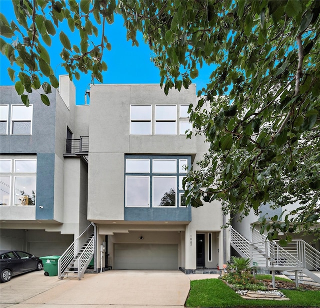 1822 Brun St, Houston, TX 77019 - townhome / multi-family property with stairway, a garage, concrete driveway, and stucco siding