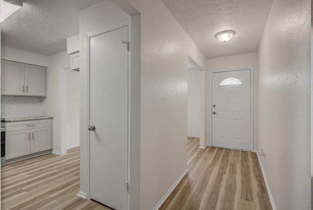 1041 Crossing Rd, Angleton, TX 77515 - doorway to outside with a textured ceiling, light wood-type flooring, and a textured wall