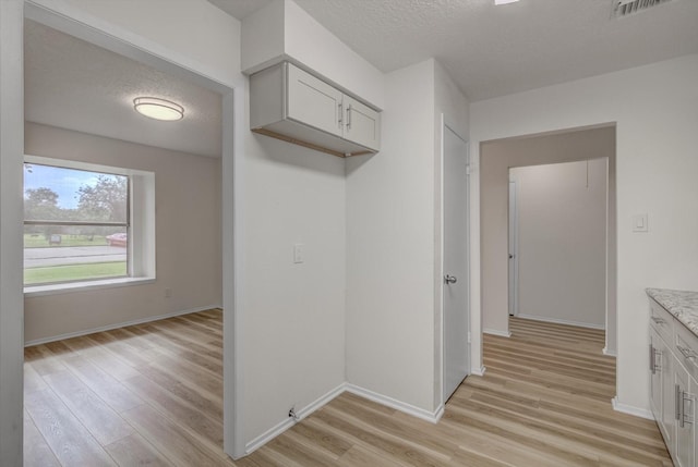 1041 Crossing Rd, Angleton, TX 77515 - kitchen featuring light wood-style flooring, a textured ceiling, and white cabinetry