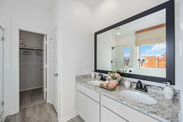 506 Tejas Village Pkwy, Beasley, TX 77417 - bathroom with a shower stall, a walk in closet, wood finished floors, and double vanity