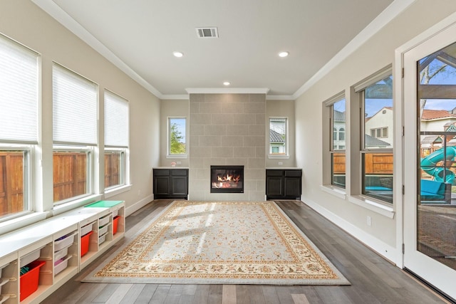 5807 Yango Terrace Ln, Sugar Land, TX 77479 - living area with dark wood-style flooring, crown molding, a tiled fireplace, recessed lighting, and baseboards