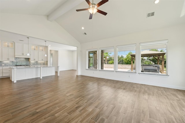 25306 Hollowgate Park Ln, Tomball, TX 77375 - unfurnished living room featuring beamed ceiling, ceiling fan, high vaulted ceiling, wood finished floors, and healthy amount of natural light