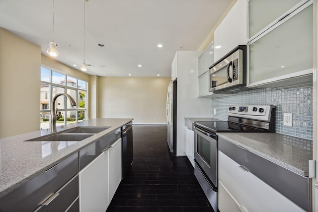 207 Pierce St Unit 205, Houston, TX 77002 - kitchen featuring appliances with stainless steel finishes, a sink, dark wood-type flooring, backsplash, and white cabinets