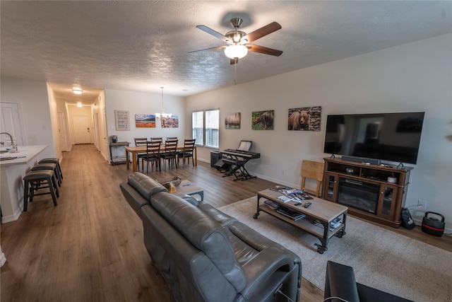 3017 Cambridge Meadows Ln, Dickinson, TX 77539 - living room with ceiling fan, wood finished floors, a chandelier, baseboards, and a textured ceiling