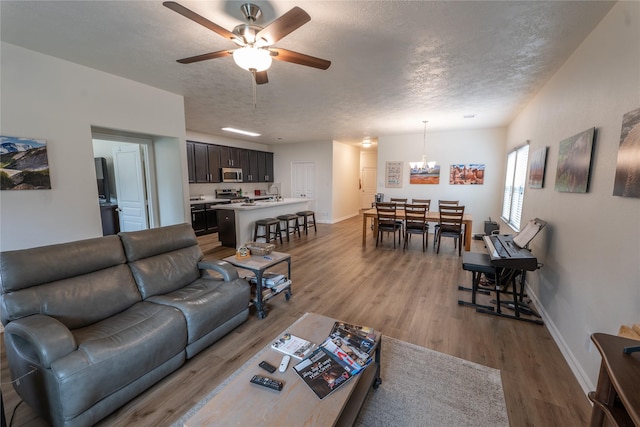 3017 Cambridge Meadows Ln, Dickinson, TX 77539 - living room with wood finished floors, baseboards, a chandelier, ceiling fan, and a textured ceiling