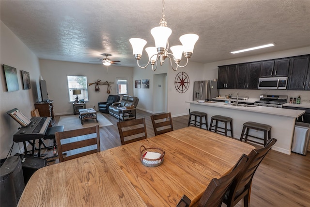 3017 Cambridge Meadows Ln, Dickinson, TX 77539 - dining room featuring a chandelier, wood finished floors, a ceiling fan, a textured ceiling, and baseboards