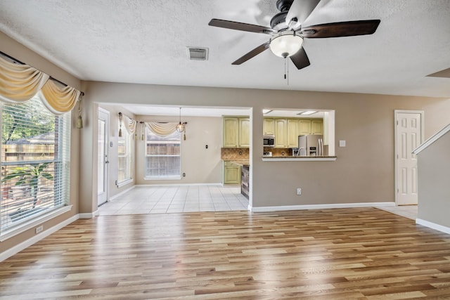 19 Almond Branch Pl, The Woodlands, TX 77382 - unfurnished living room with ceiling fan, light wood finished floors, a textured ceiling, and baseboards