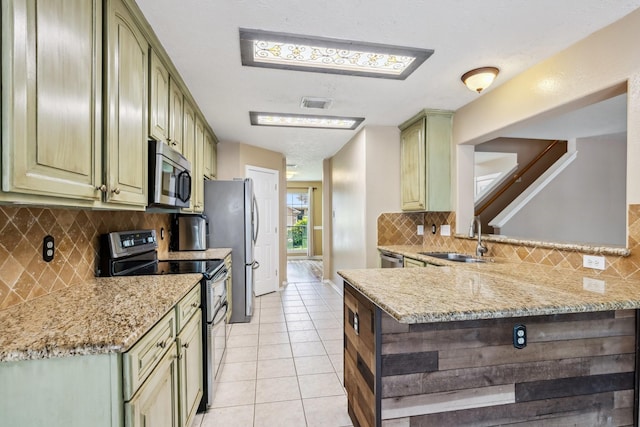 19 Almond Branch Pl, The Woodlands, TX 77382 - kitchen featuring appliances with stainless steel finishes, a sink, green cabinets, light tile patterned floors, and tasteful backsplash