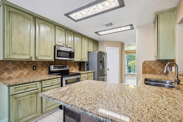 19 Almond Branch Pl, The Woodlands, TX 77382 - kitchen featuring stainless steel appliances, a sink, green cabinetry, a peninsula, and tasteful backsplash