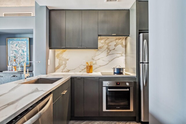 3614 Montrose Blvd Unit 704, Houston, TX 77006 - kitchen featuring appliances with stainless steel finishes, decorative backsplash, light stone counters, a sink, and modern cabinets