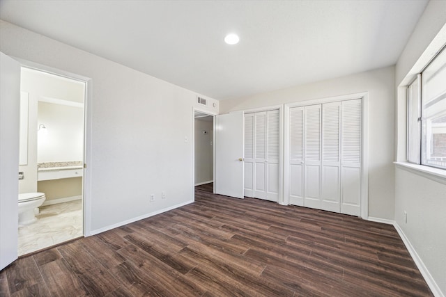 4040 San Felipe St Unit 246, Houston, TX 77027 - unfurnished bedroom with dark wood-style flooring, two closets, ensuite bathroom, baseboards, and recessed lighting
