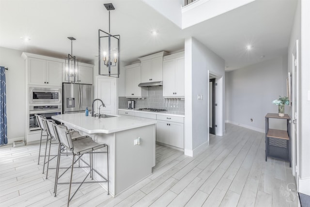 5106 Green Leaf Ln, Fulshear, TX 77441 - kitchen featuring stainless steel appliances, under cabinet range hood, backsplash, a kitchen breakfast bar, and a sink