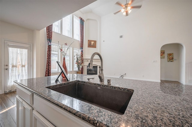 11202 Bluewater Lagoon Cir, Cypress, TX 77433 - kitchen featuring a sink, arched walkways, dark stone countertops, a towering ceiling, and a ceiling fan