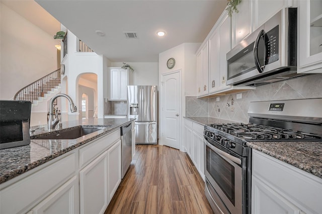 11202 Bluewater Lagoon Cir, Cypress, TX 77433 - kitchen with appliances with stainless steel finishes, a sink, white cabinetry, arched walkways, and stone countertops