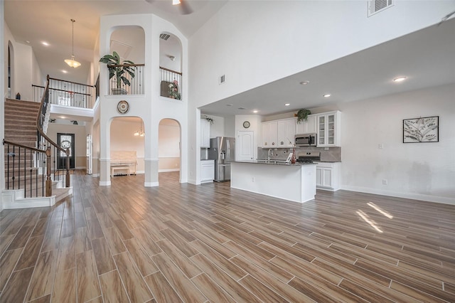11202 Bluewater Lagoon Cir, Cypress, TX 77433 - unfurnished living room featuring baseboards, stairs, wood finished floors, a sink, and a towering ceiling