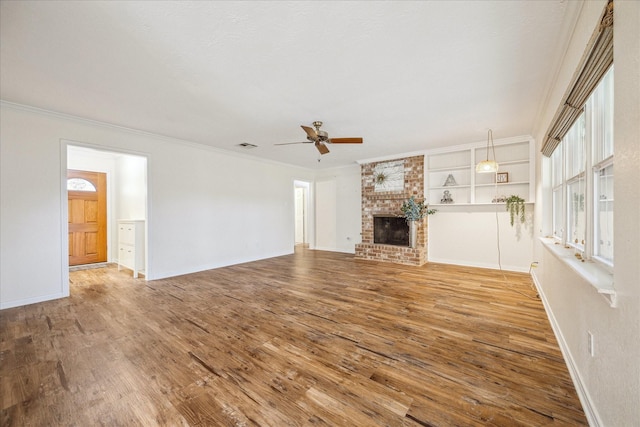 507 Williamsport St, League City, TX 77573 - unfurnished living room featuring a ceiling fan, ornamental molding, wood finished floors, a brick fireplace, and baseboards