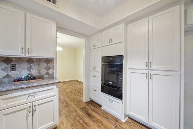 507 Williamsport St, League City, TX 77573 - kitchen with oven, a warming drawer, light wood-type flooring, decorative backsplash, and white cabinets