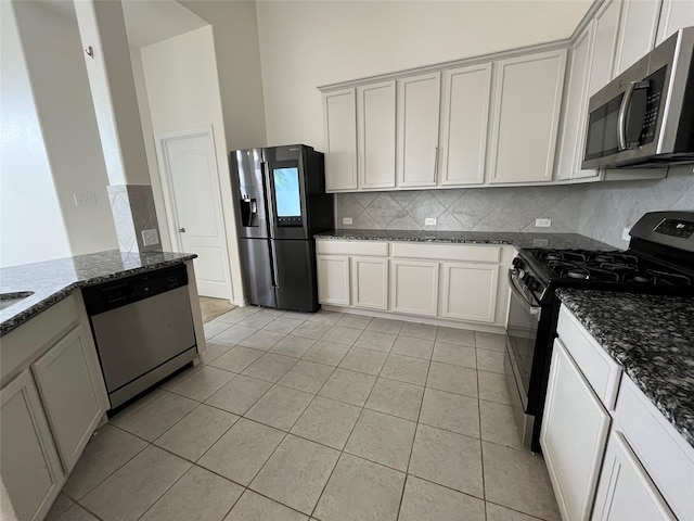 31909 Mckinley Run Dr, Hockley, TX 77447 - kitchen featuring appliances with stainless steel finishes, backsplash, light tile patterned flooring, and dark stone countertops